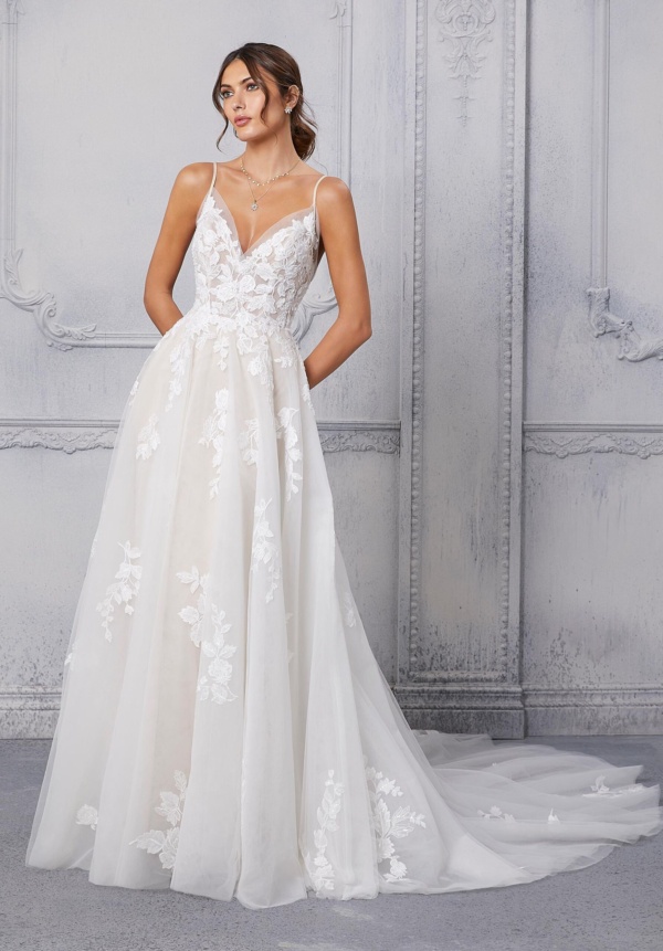 Our Carita gown embodies sweet simplicity. The dreamy A-line ball gown has a sheer, v-neck bodice accented by lovely crystal beaded, frosted embroidered appliqués.